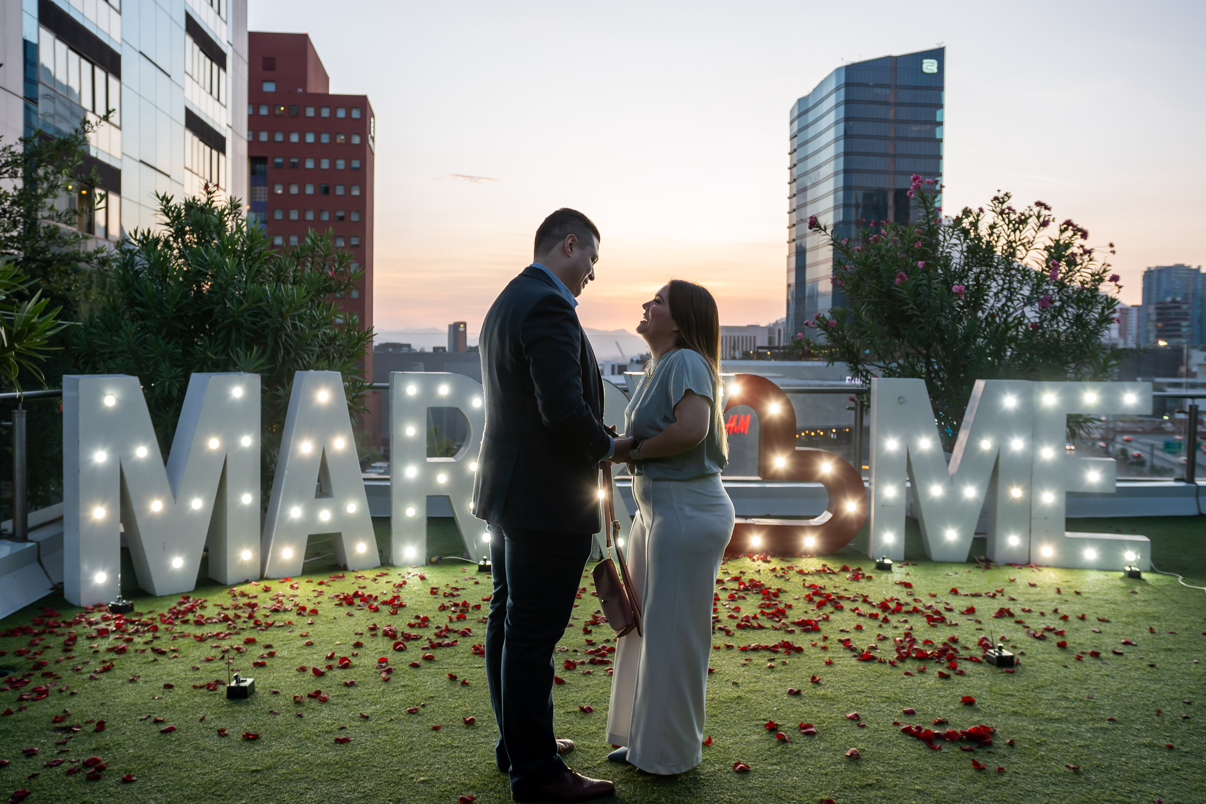 Pareja tomada de las manos en momento de sorpresa con vista nocturna de Monterrey