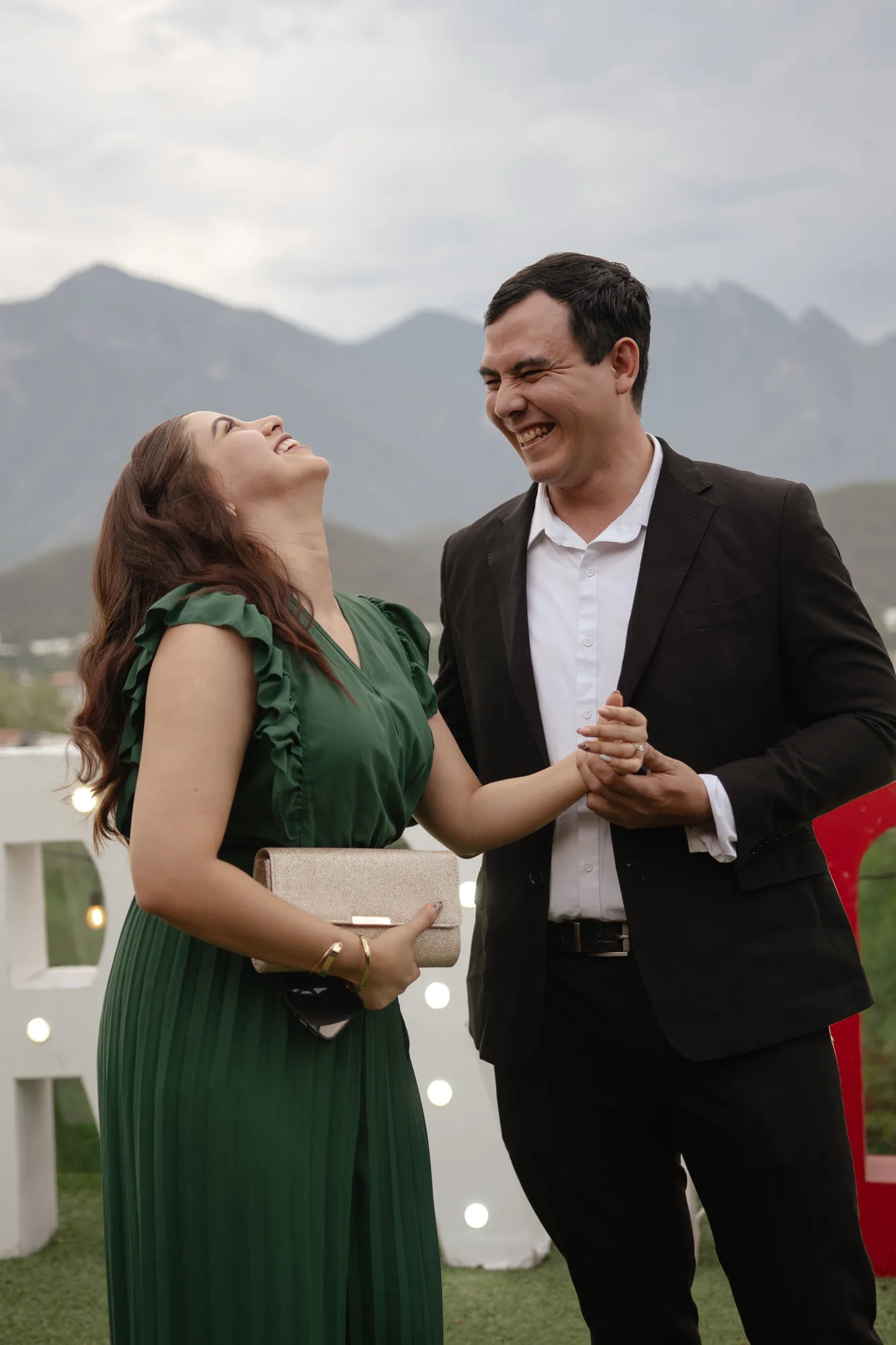Pareja riendo a carcajadas frente al Cerro de la Silla con luz natural suave